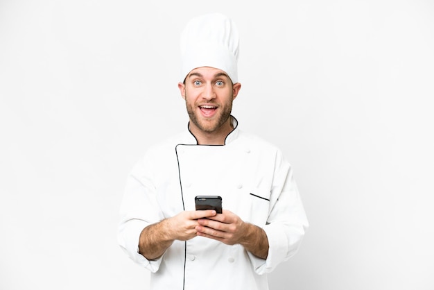 Young blonde man Chef over isolated white background surprised and sending a message