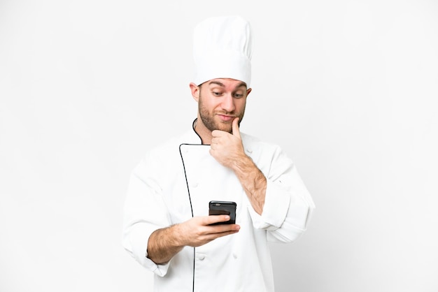 Young blonde man Chef over isolated white background thinking and sending a message