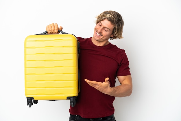 Young blonde man isolated on white background in vacation with travel suitcase