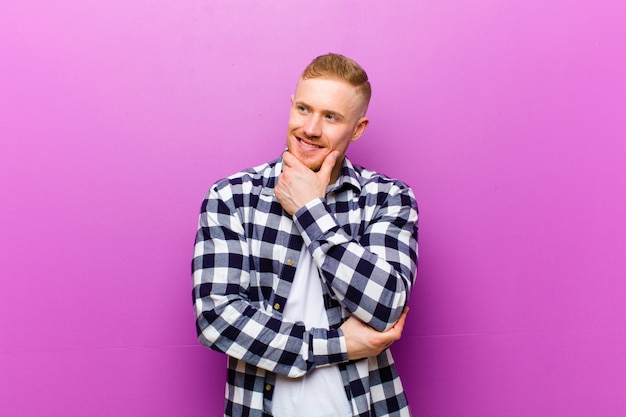 young blonde man with hand on chin wondering and looking to the side