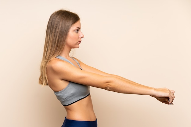 Photo young blonde sport girl over isolated wall stretching