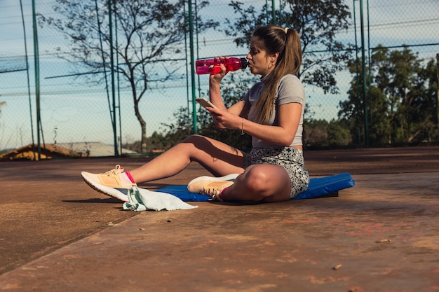 Young blonde sportswoman drinking water