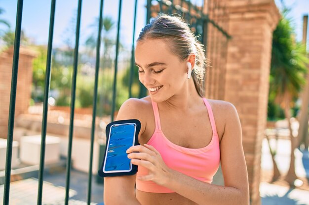 Young blonde sportswoman using earphones doing exercise at the city