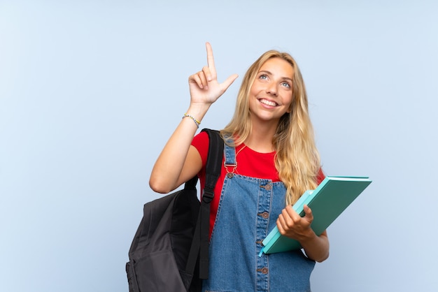 Young blonde student woman over isolated blue wall pointing with the index finger a great idea