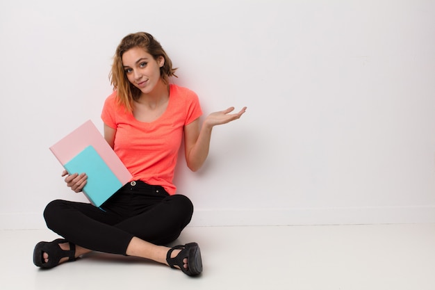 Young blonde woman  against  wall with books