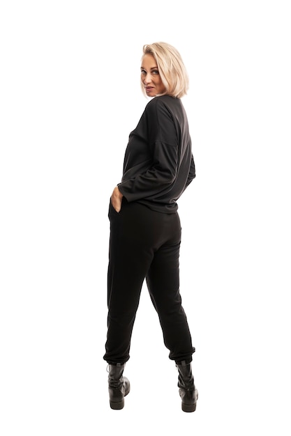 Young blonde woman in black casual suit and rough boots. Full height. Back view. Isolated