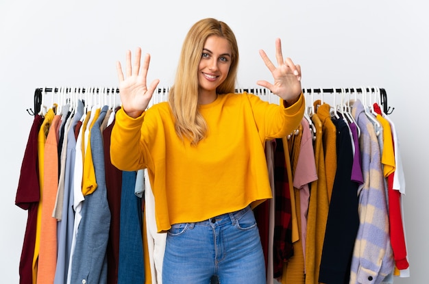 Young blonde woman in a clothing store counting eight with fingers