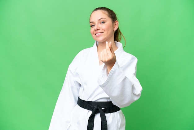 Young blonde woman doing karate over isolated chroma key background making money gesture