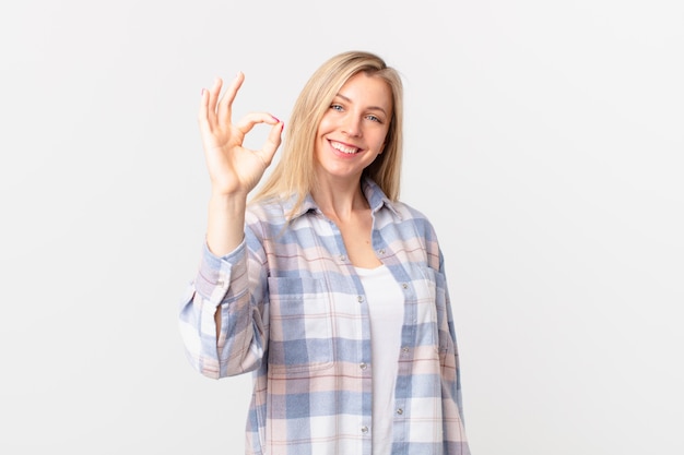 Young blonde woman feeling happy, showing approval with okay gesture