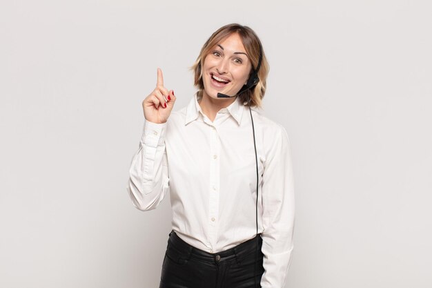 Young blonde woman feeling like a happy and excited genius after realizing an idea cheerfully raising finger eureka