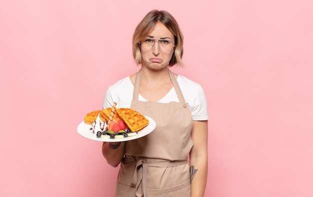 Young blonde woman feeling sad and whiney with an unhappy look, crying with a negative and frustrated attitude