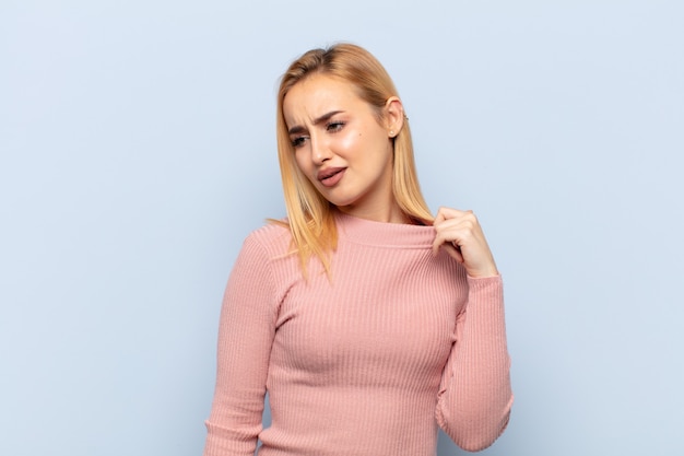 Young blonde woman feeling stressed, anxious, tired and frustrated, pulling shirt neck, looking frustrated with problem