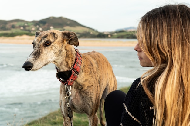 Young blonde woman and her greyhound on the shore