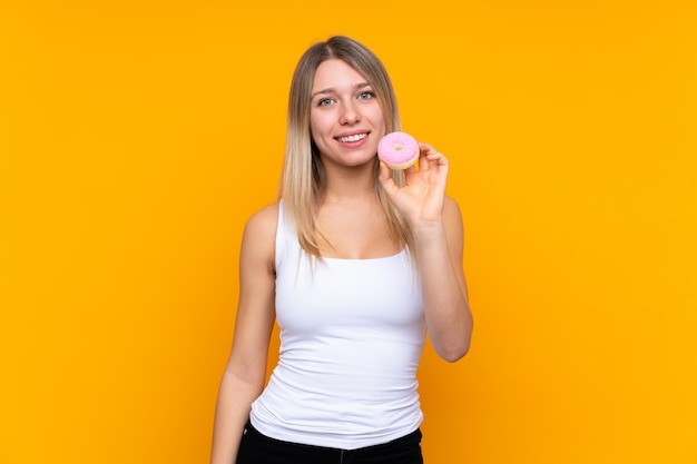 Young blonde woman holding a donut and happy