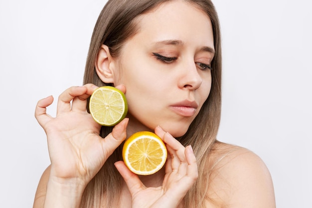 A young blonde woman holding a halfs a lime and a lemon in her hands Natural cosmetics