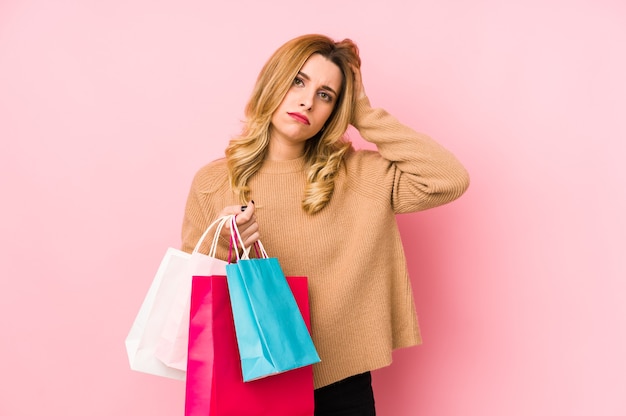 Young blonde woman holding shopping bags isolated being shocked, she has remembered important meeting.