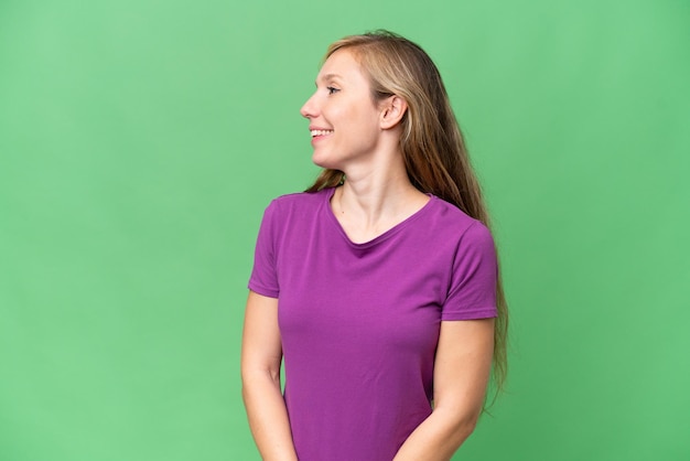 Young blonde woman over isolated background looking to the side and smiling