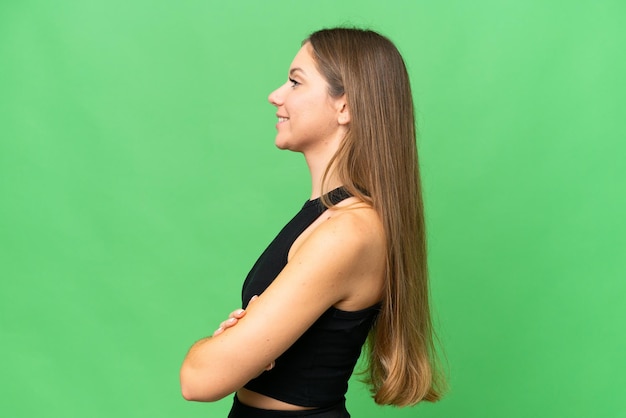 Young blonde woman over isolated chroma key background in lateral position