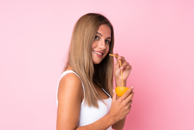 Young blonde woman over isolated  holding an orange