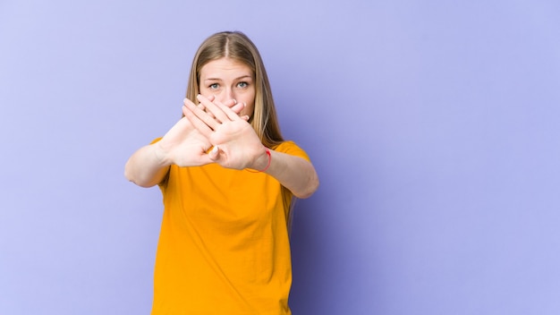 Young blonde woman isolated on purple,  doing a denial gesture