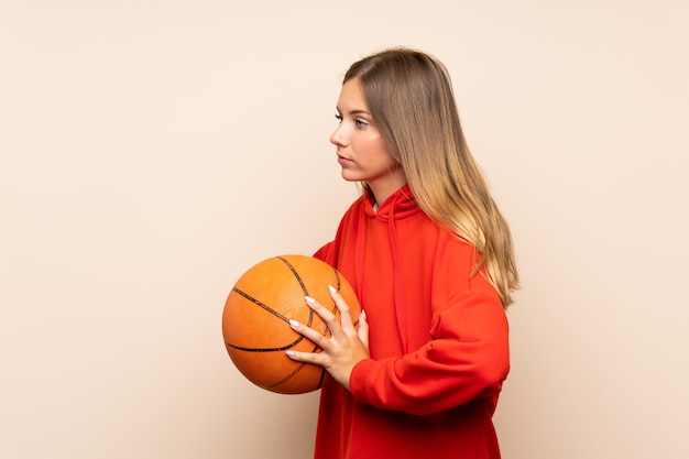 Young blonde woman over isolated wall with ball of basketball