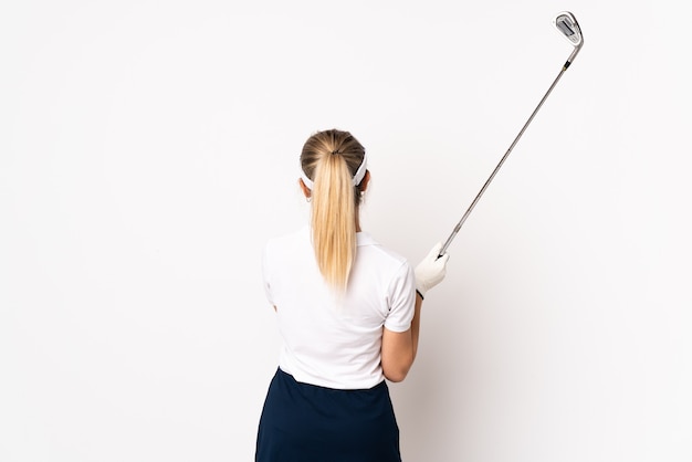 Young blonde woman isolated on white wall playing golf