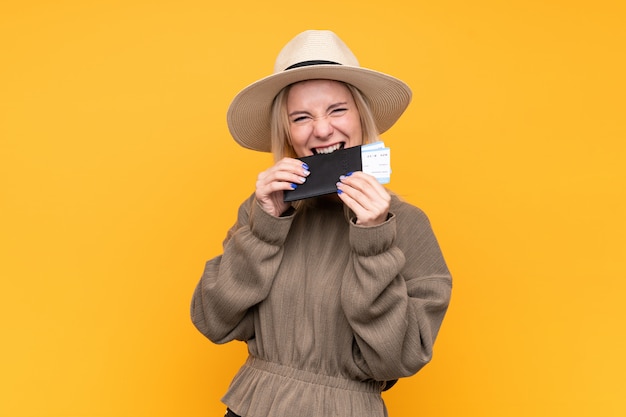 Young blonde woman over isolated yellow wall holding a passport