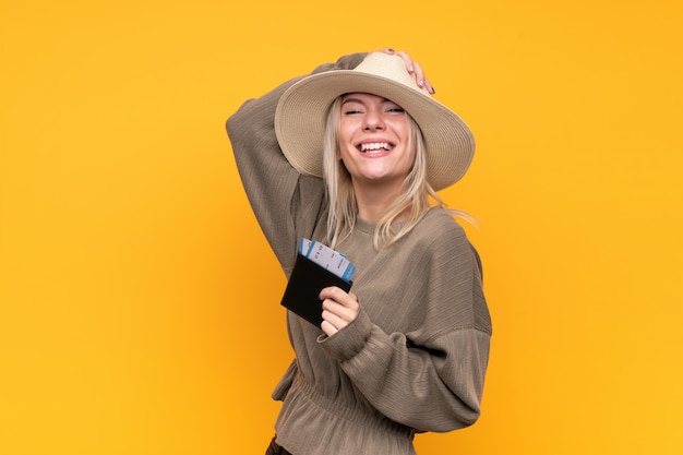 Young blonde woman over isolated yellow wall holding a passport