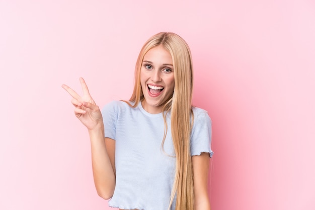 Young blonde woman joyful and carefree showing a peace symbol with fingers