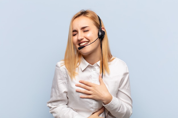 Young blonde woman laughing out loud at some hilarious joke, feeling happy and cheerful, having fun