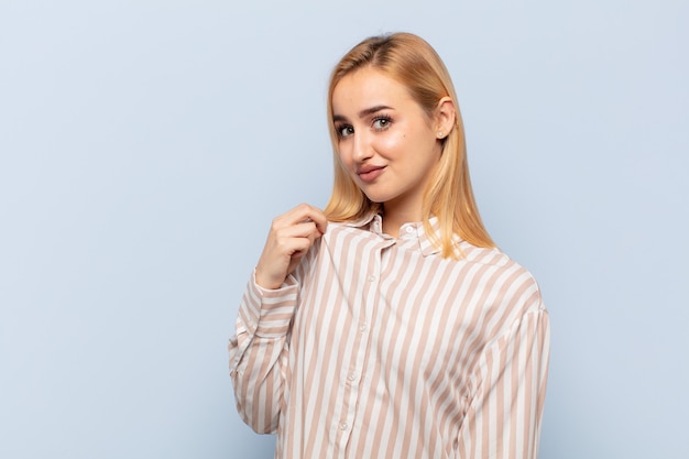 Young blonde woman looking arrogant, successful, positive and proud, pointing to self