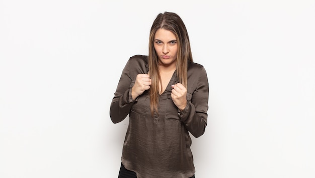 Young blonde woman looking confident, angry, strong and aggressive, with fists ready to fight in boxing position