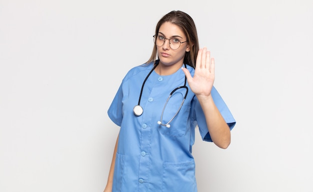 Young blonde woman looking serious, stern, displeased and angry showing open palm making stop gesture