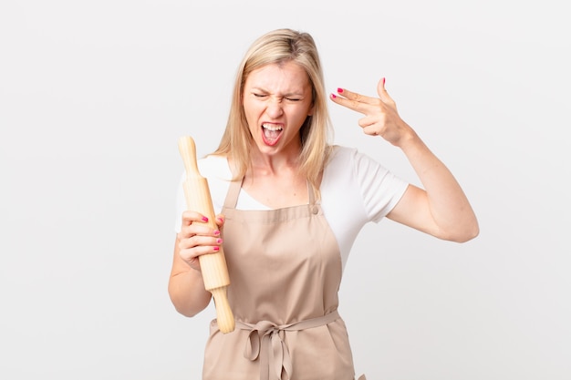 Young blonde woman looking unhappy and stressed, suicide gesture making gun sign. baker concept