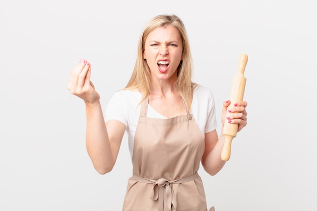 Young blonde woman making capice or money gesture, telling you to pay. baker concept