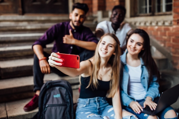 Young blonde woman making selfie with her friends students in universit