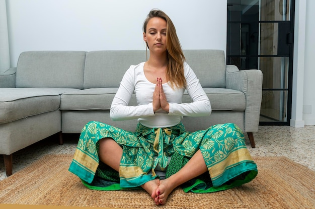 Young blonde woman meditating in the living room at home