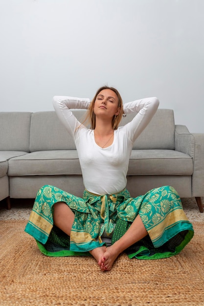 Young blonde woman meditating in the living room at home