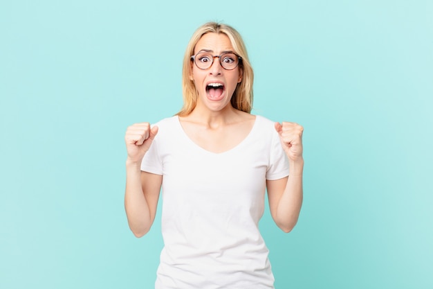 Young blonde woman shouting aggressively with an angry expression