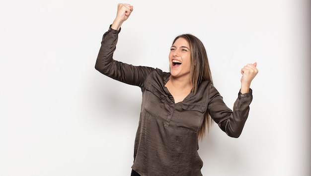 Young blonde woman shouting triumphantly, looking like excited, happy and surprised winner, celebrating