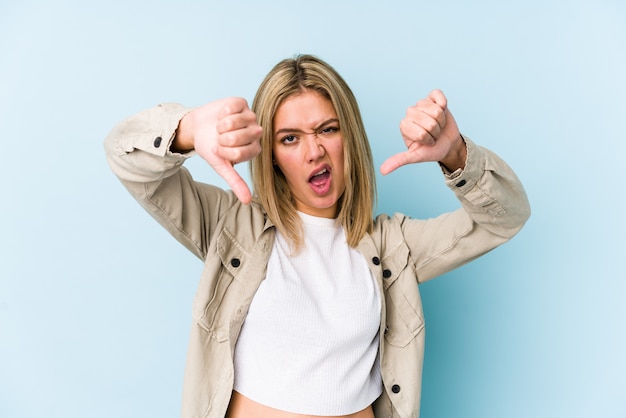 Young blonde woman showing thumb down and expressing dislike