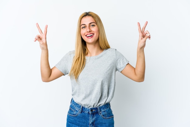 Young blonde woman showing victory sign and smiling broadly.