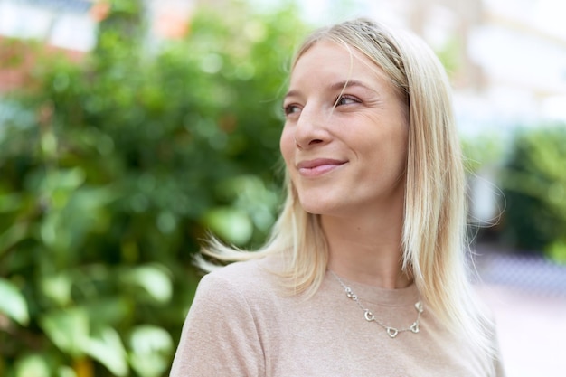 Young blonde woman smiling confident looking to the side at park