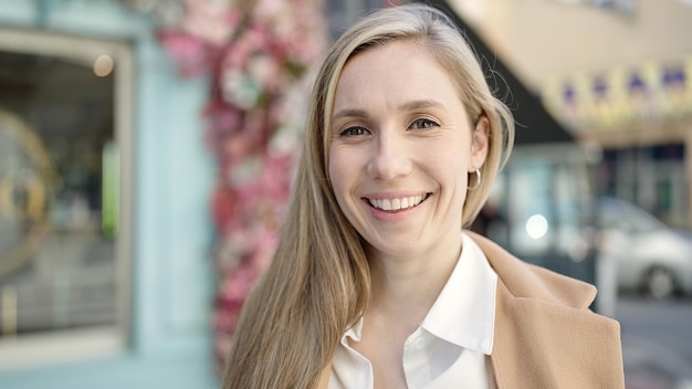 Young blonde woman smiling confident standing at coffee shop terrace