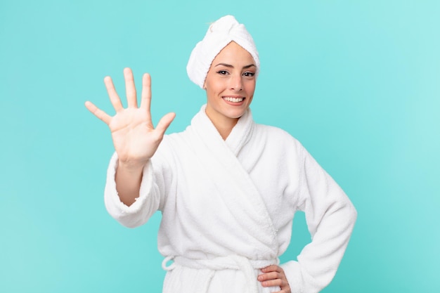 Young blonde woman smiling and looking friendly, showing number five. shower concept.