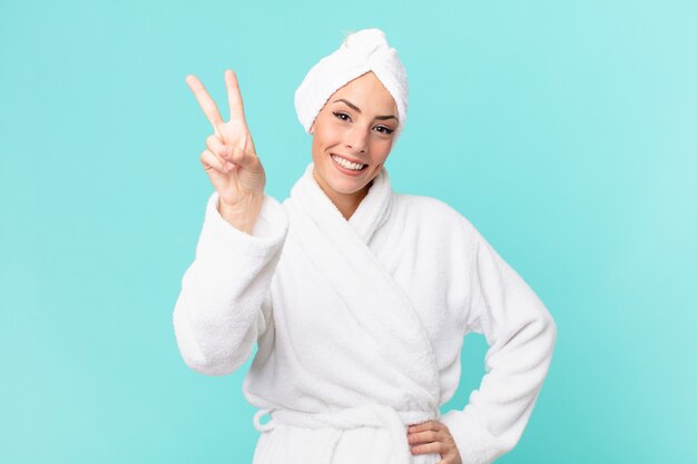 Young blonde woman smiling and looking happy, gesturing victory or peace. shower concept.