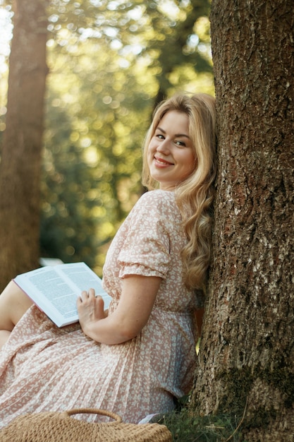 Young blonde woman in summer park reads book