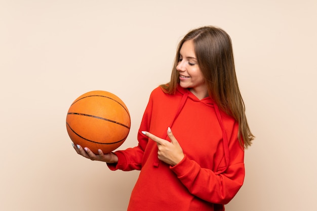 Young blonde woman with ball of basketball and pointing it