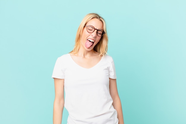 Young blonde woman with cheerful and rebellious attitude, joking and sticking tongue out