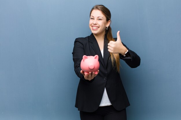 Young blonde woman with a piggy bank against grunge wall